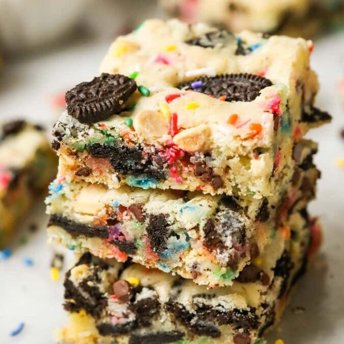Stack of three funfetti Oreo bars punctuated with bits of Oreo cookies and sprinkles.