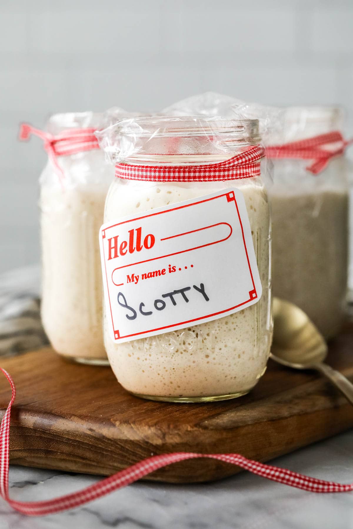 Jar of active sourdough starter with a nametag on it reading 