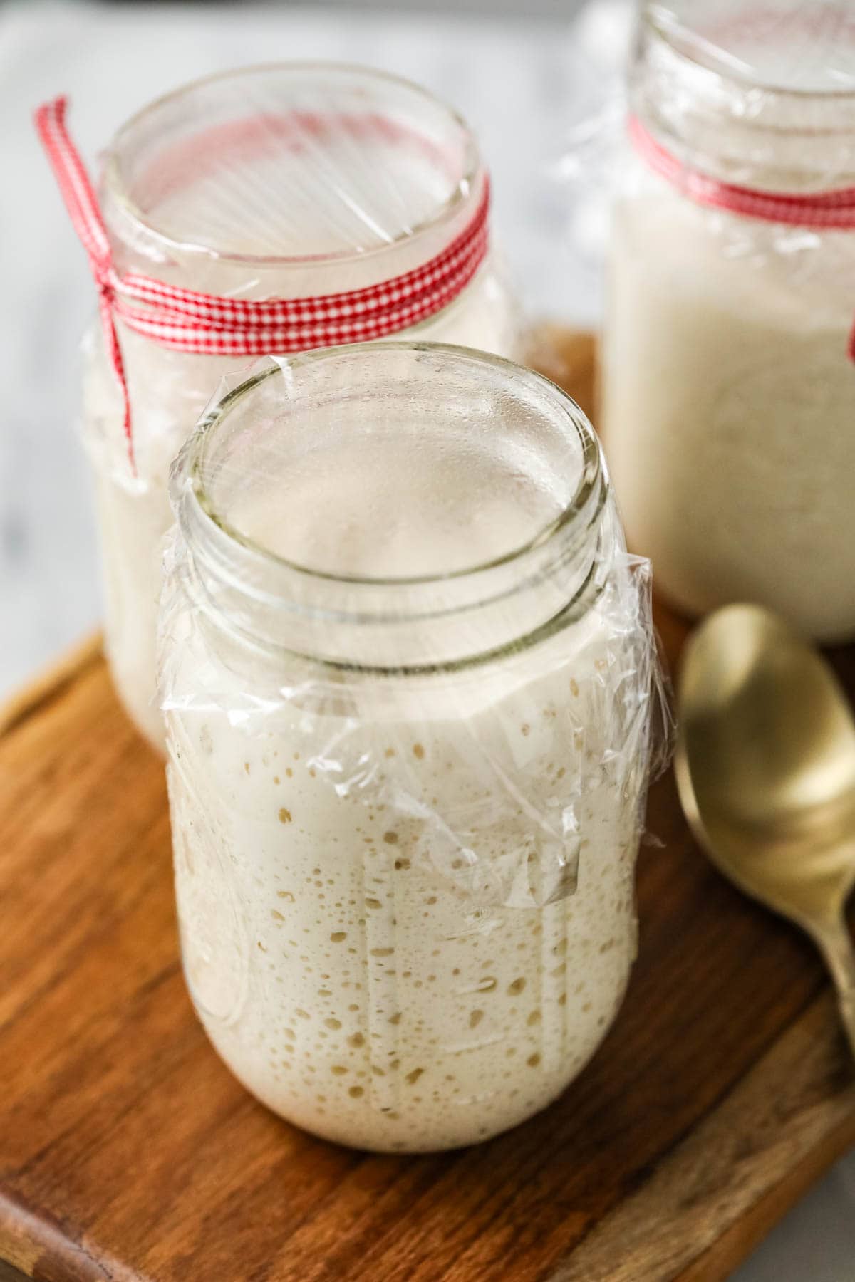 Active bubbly starter covered in mason jar with plastic wrap