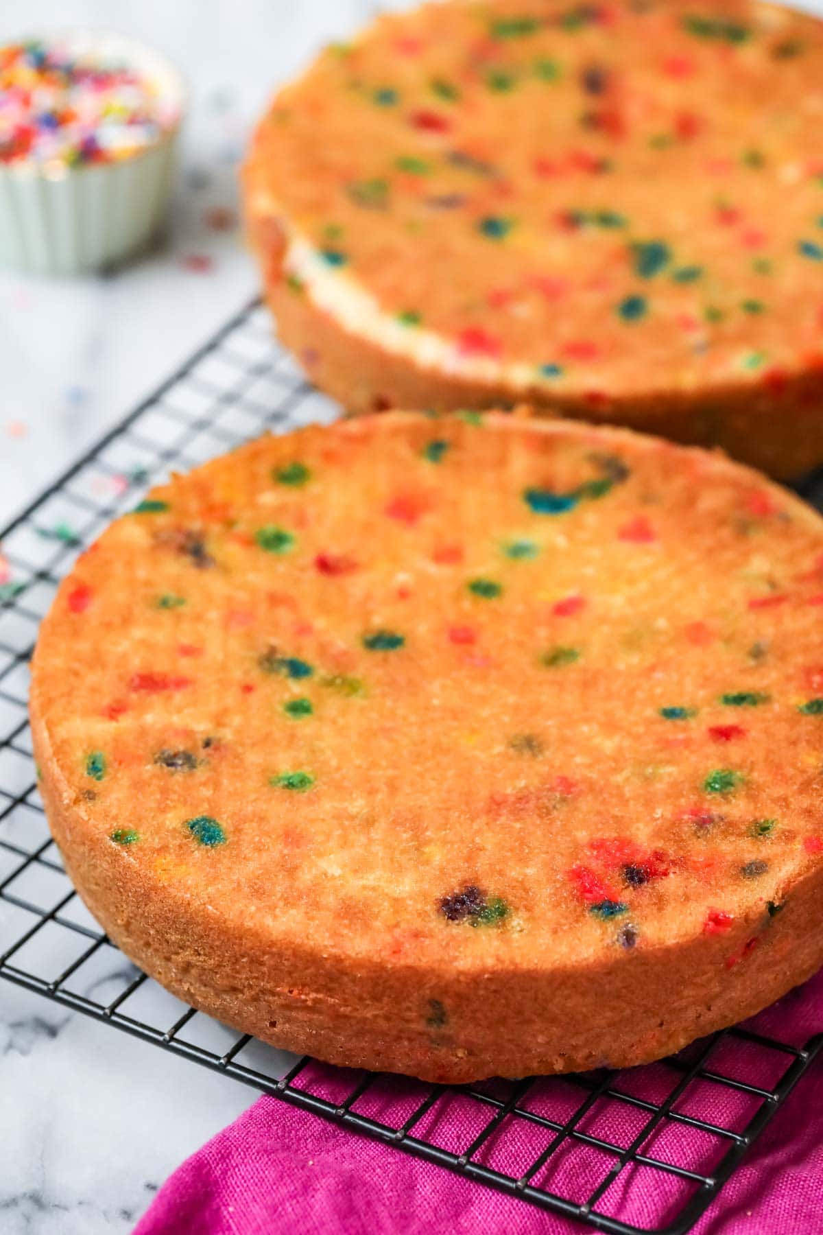 Two funfetti cake layers on a cooling rack after baking.