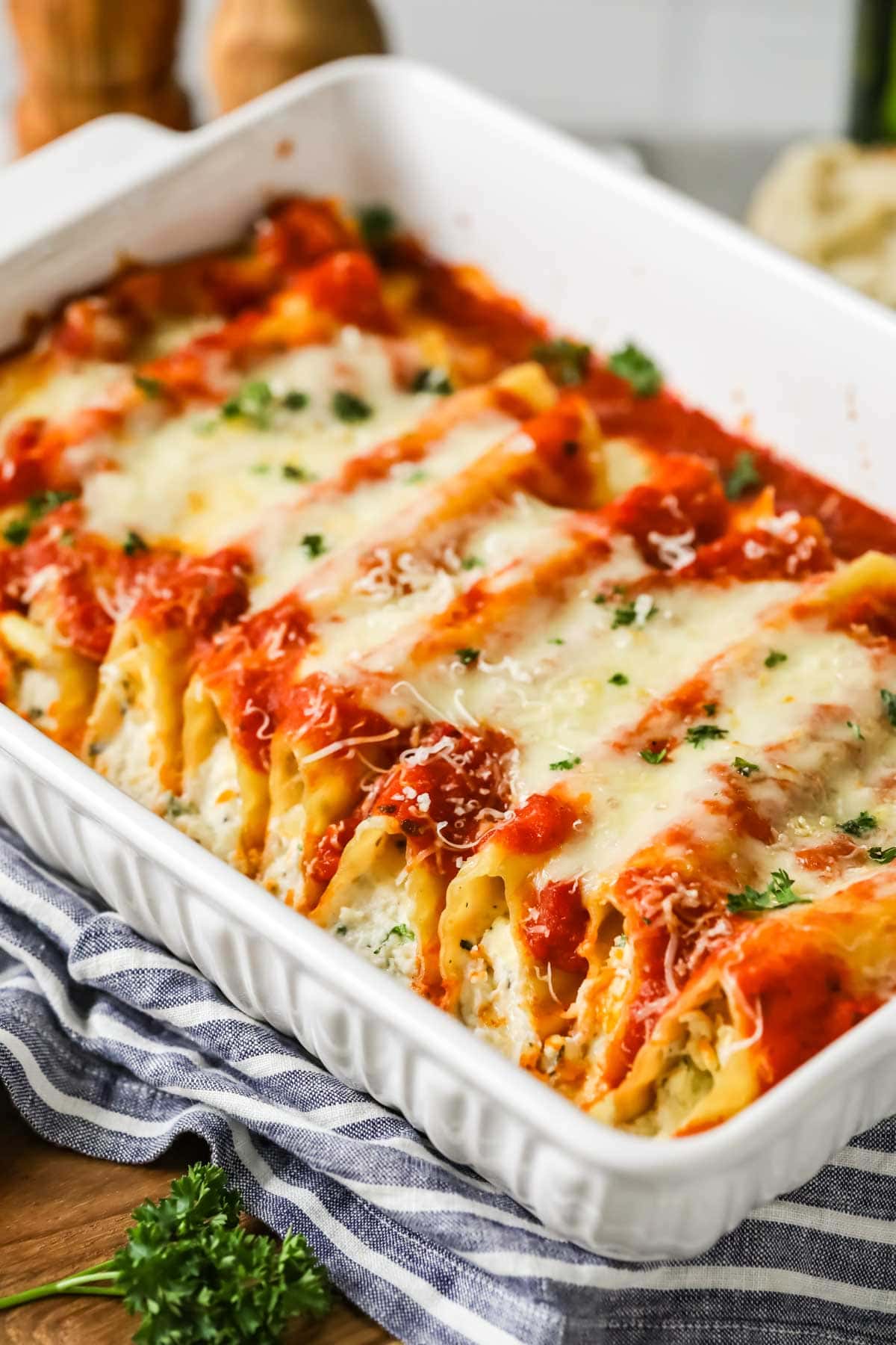 Manicotti in a casserole dish topped with sauce and cheese.