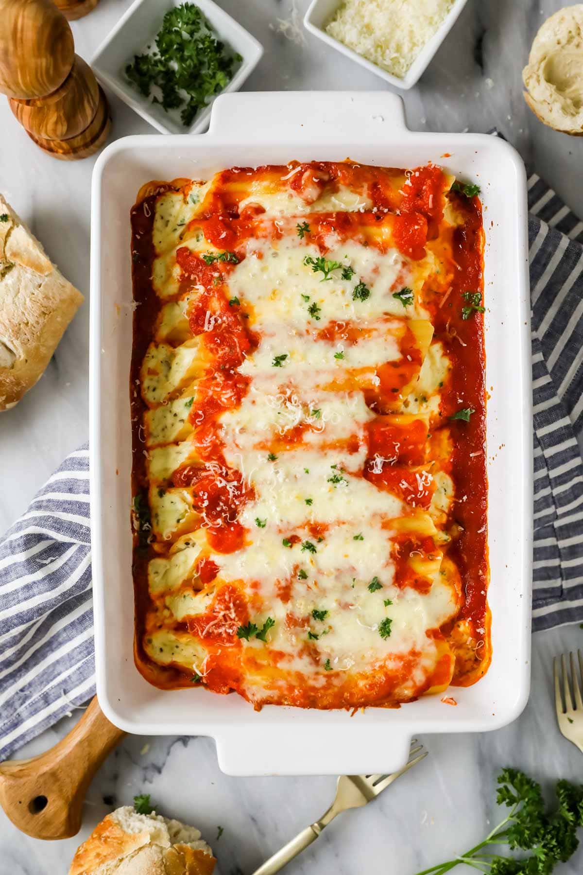 Overhead view of a casserole dish of pasta filled with ricotta and other cheeses topped with sauce and baked.