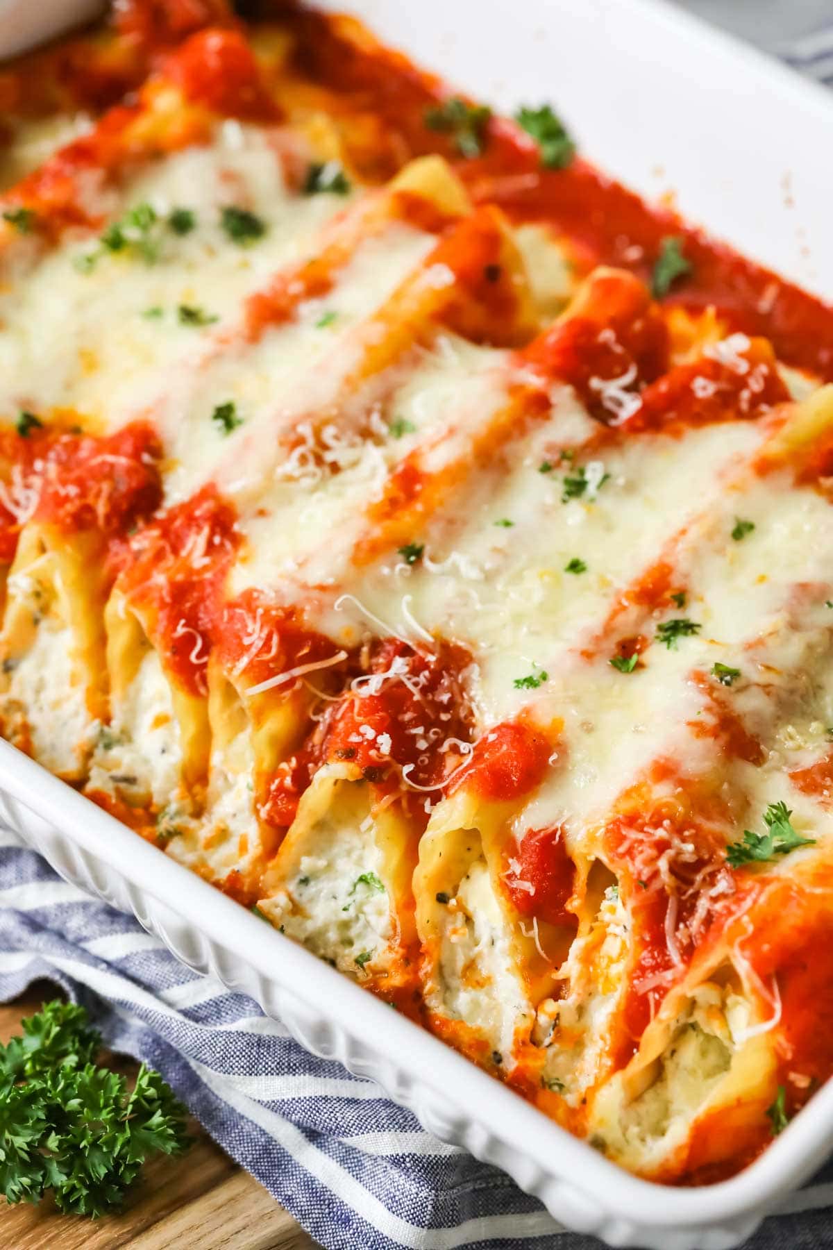 Manicotti in a casserole dish topped with sauce and cheese.