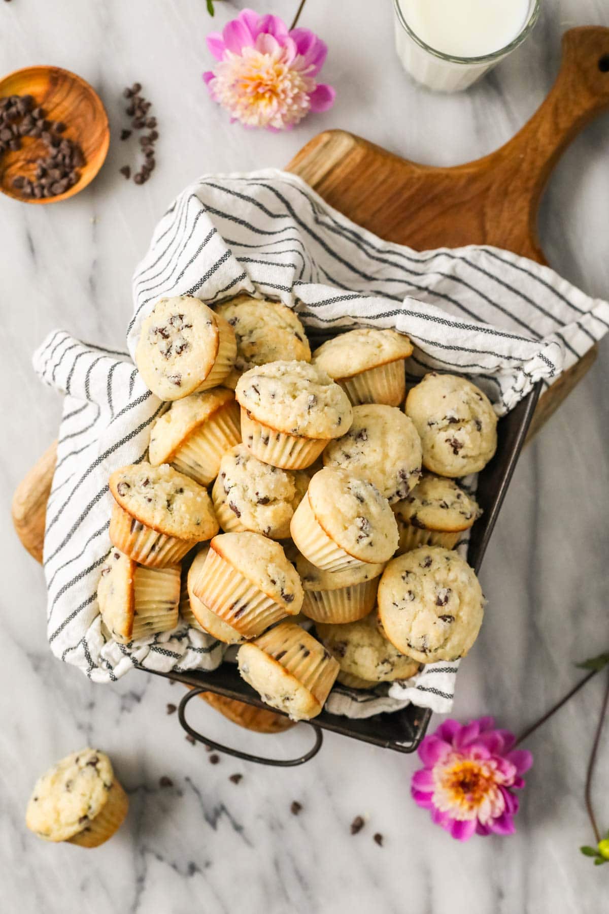 Overhead view of mini muffins in a baking pan lined with a striped tea towel.