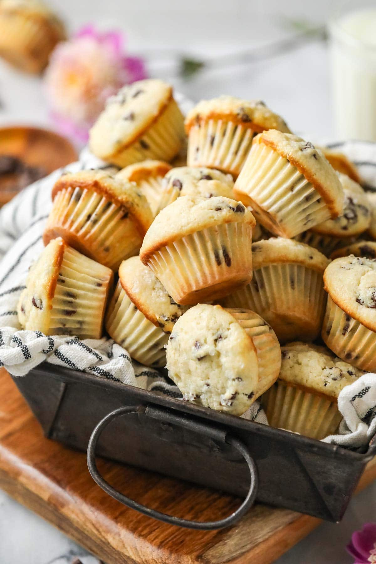 Bite sized muffins made with mini chocolate chips in a towel lined baking pan.