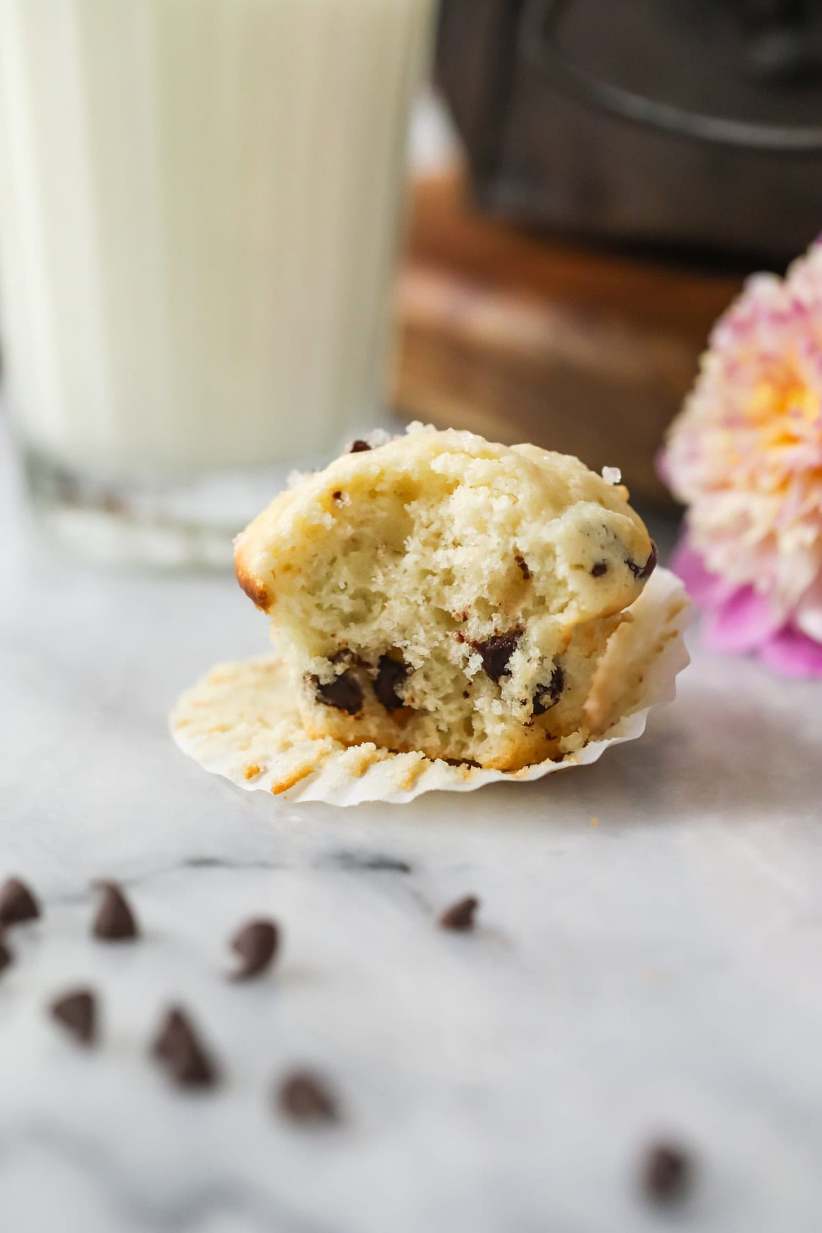 Small muffin made with mini chocolate chips with one bite missing.