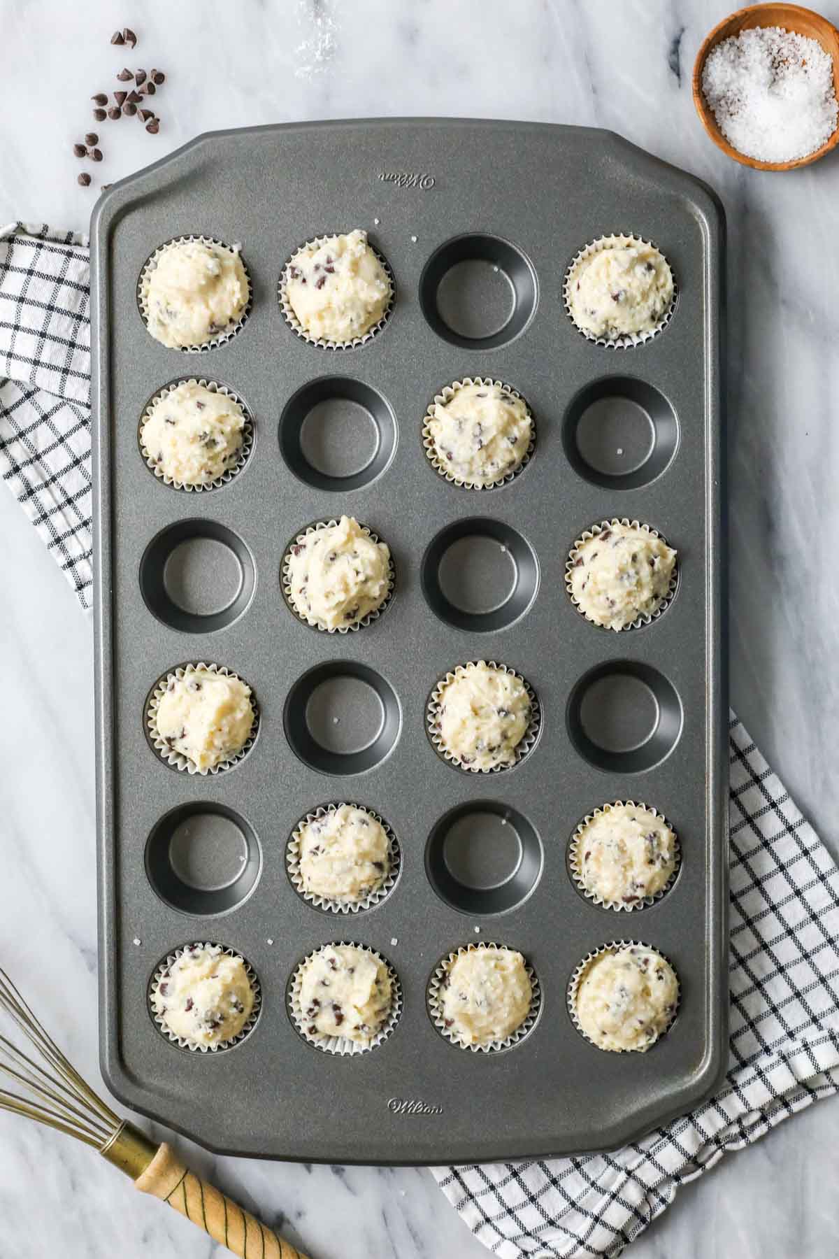 Overhead view of a mini muffin tin with batter portioned in almost every other cavity.