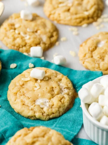 Rice krispie cookies surrounded by mini marshmallows and cereal pieces.