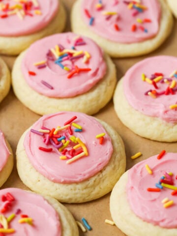 Overhead view of rows of soft frosted sugar cookies topped with pink frosting and sprinkles.