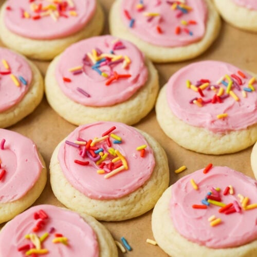 Overhead view of rows of soft frosted sugar cookies topped with pink frosting and sprinkles.