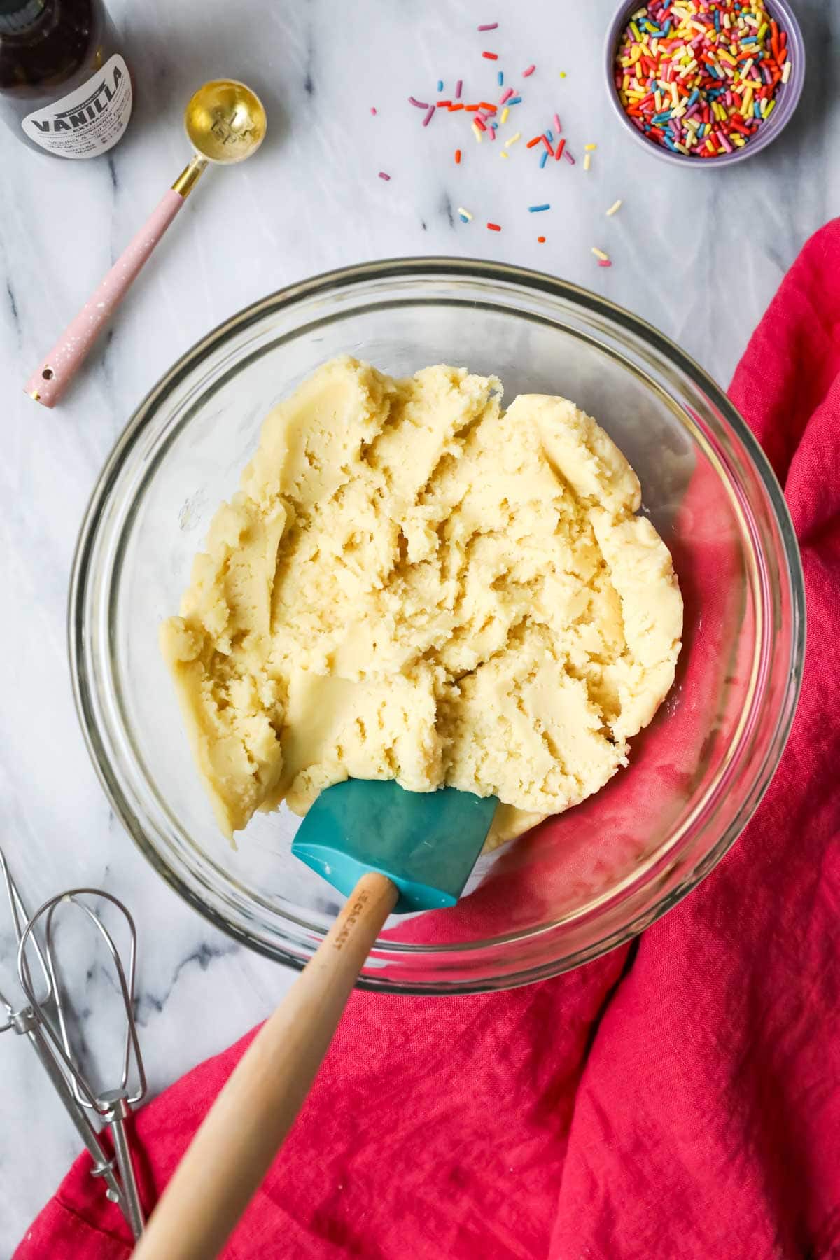 Overhead view of a bowl of sugar cookie dough with a turquoise spatula.