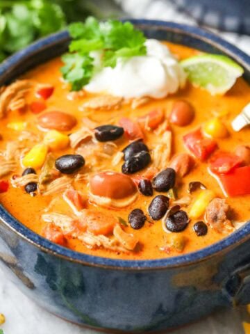 Bowl of creamy southwest chicken soup made with beans, chicken, peppers, and more.