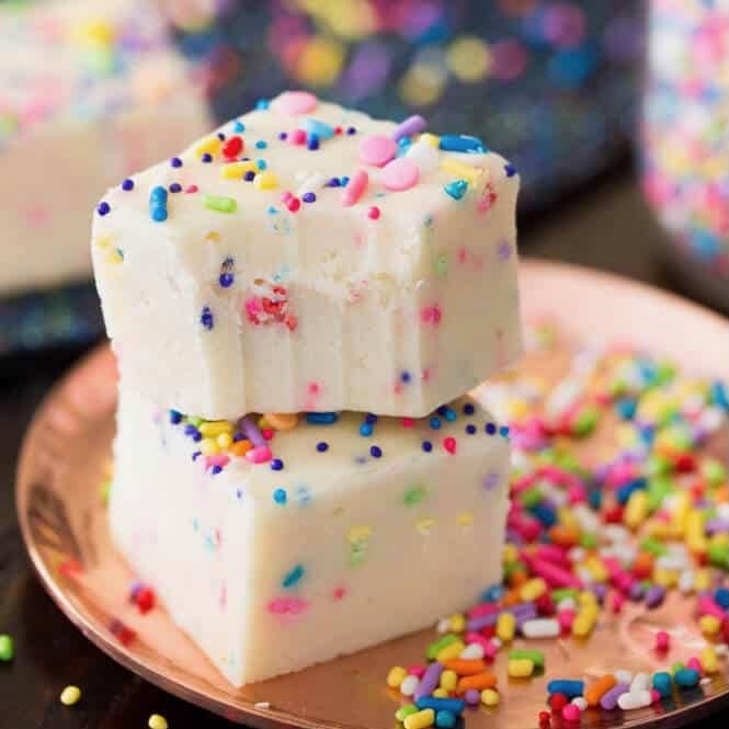 Two pieces of cake batter fudge stacked on top of each other with the top piece missing a bite.