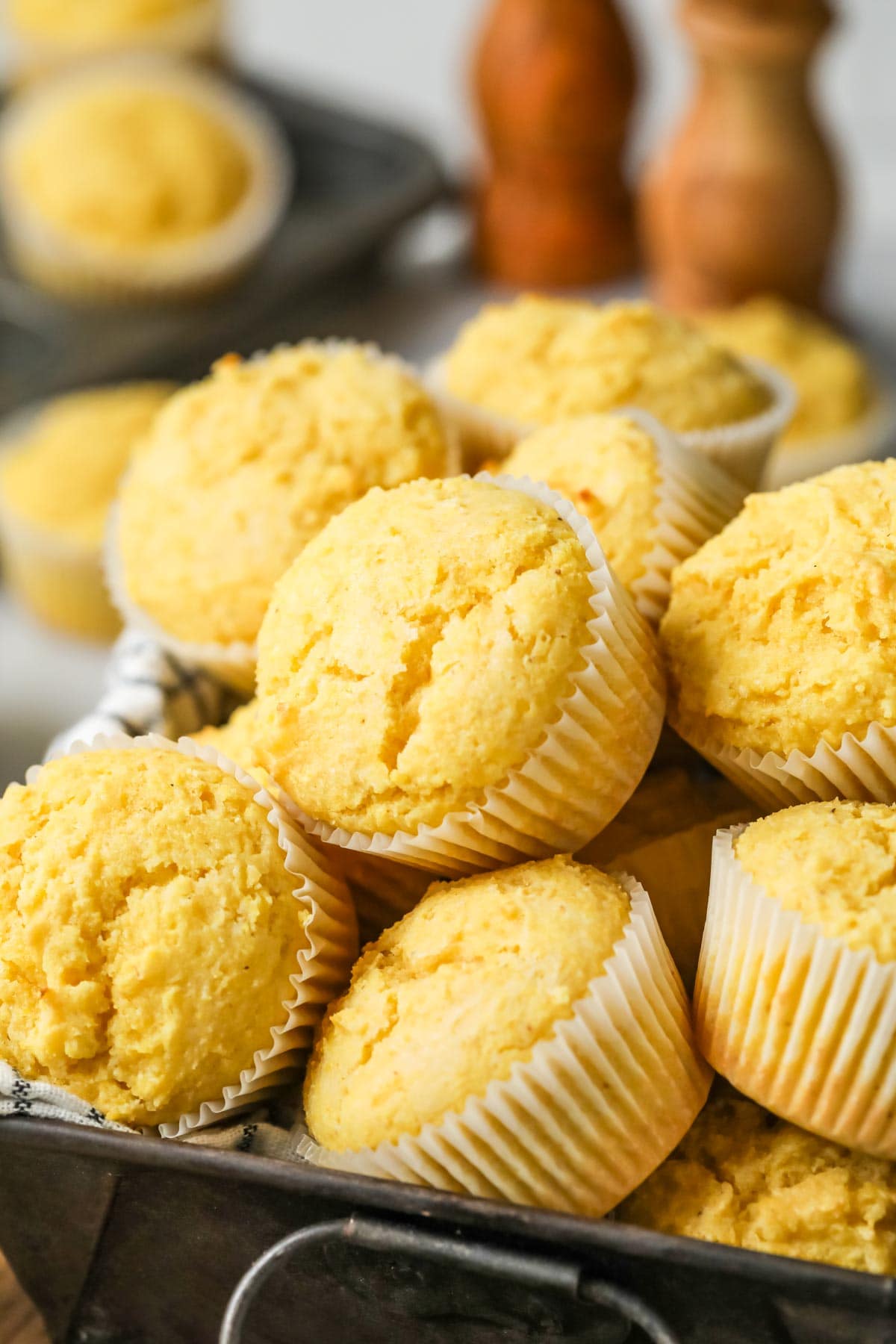 Pile of corn muffins in white muffin wrappers.