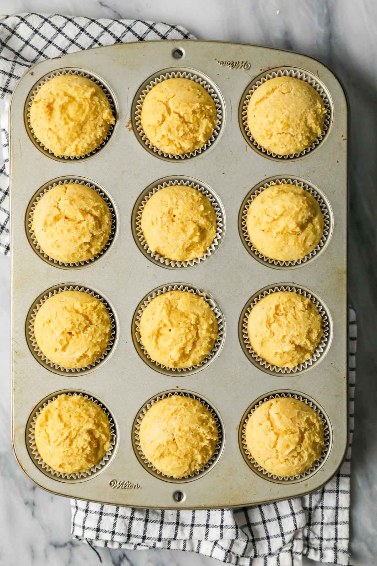 Overhead view of cornbread muffins in a pan after baking.