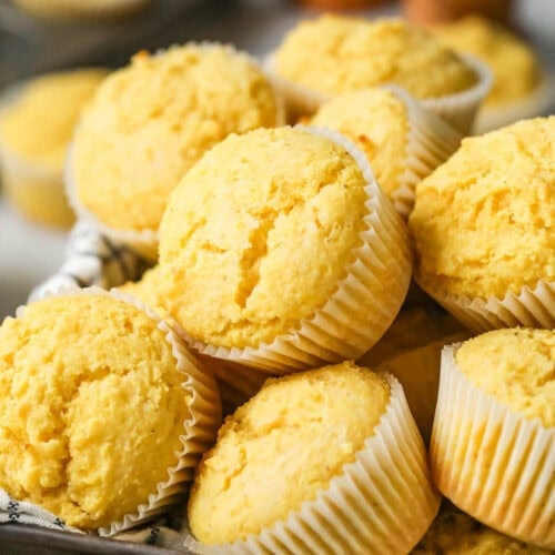 Pile of corn muffins in white muffin wrappers.