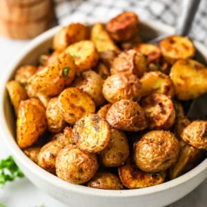 A bowl of crispy, golden oven-roasted potatoes.