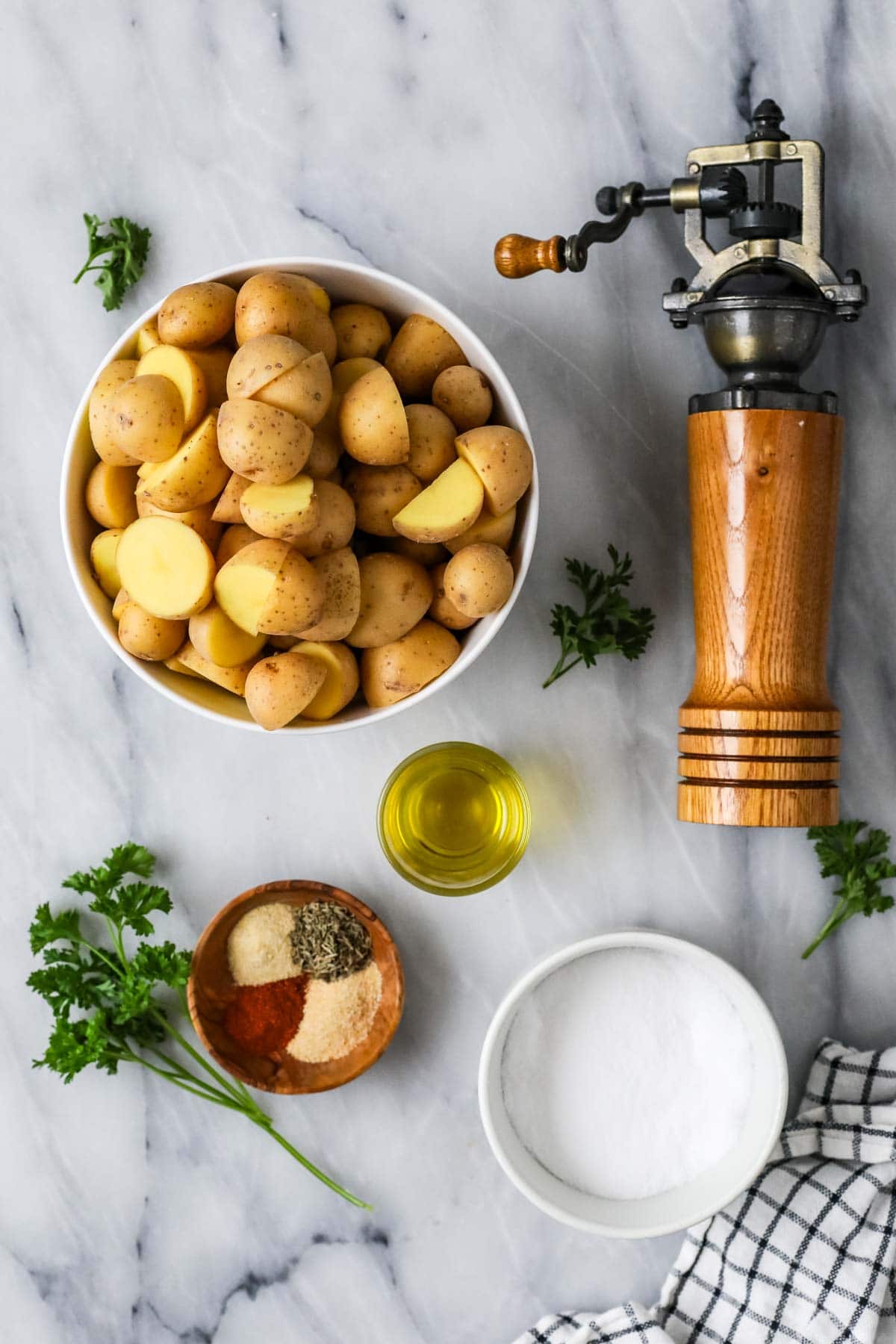 Top view of potatoes, olive oil, spices and fresh parsley.