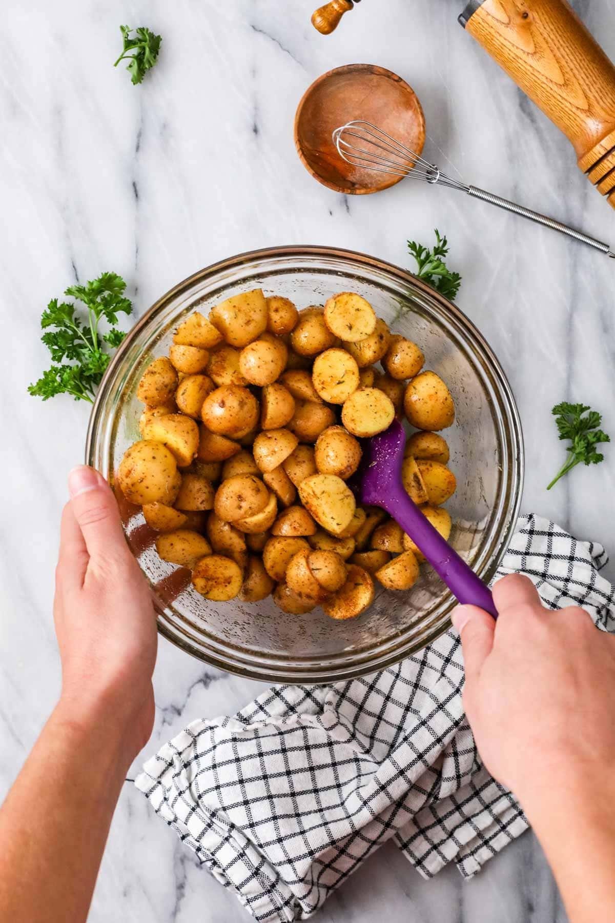 Top view of a bowl of baby potatoes tossed in olive oil and spices.