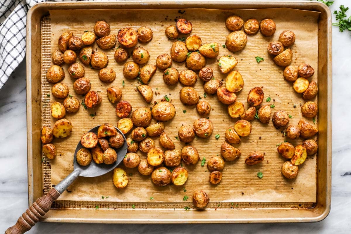 Top view of a plate of baby potatoes baking in the oven.