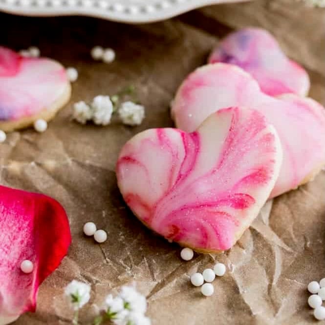 Swirled heart cookies surrounded by baby's breath on parchment paper.
