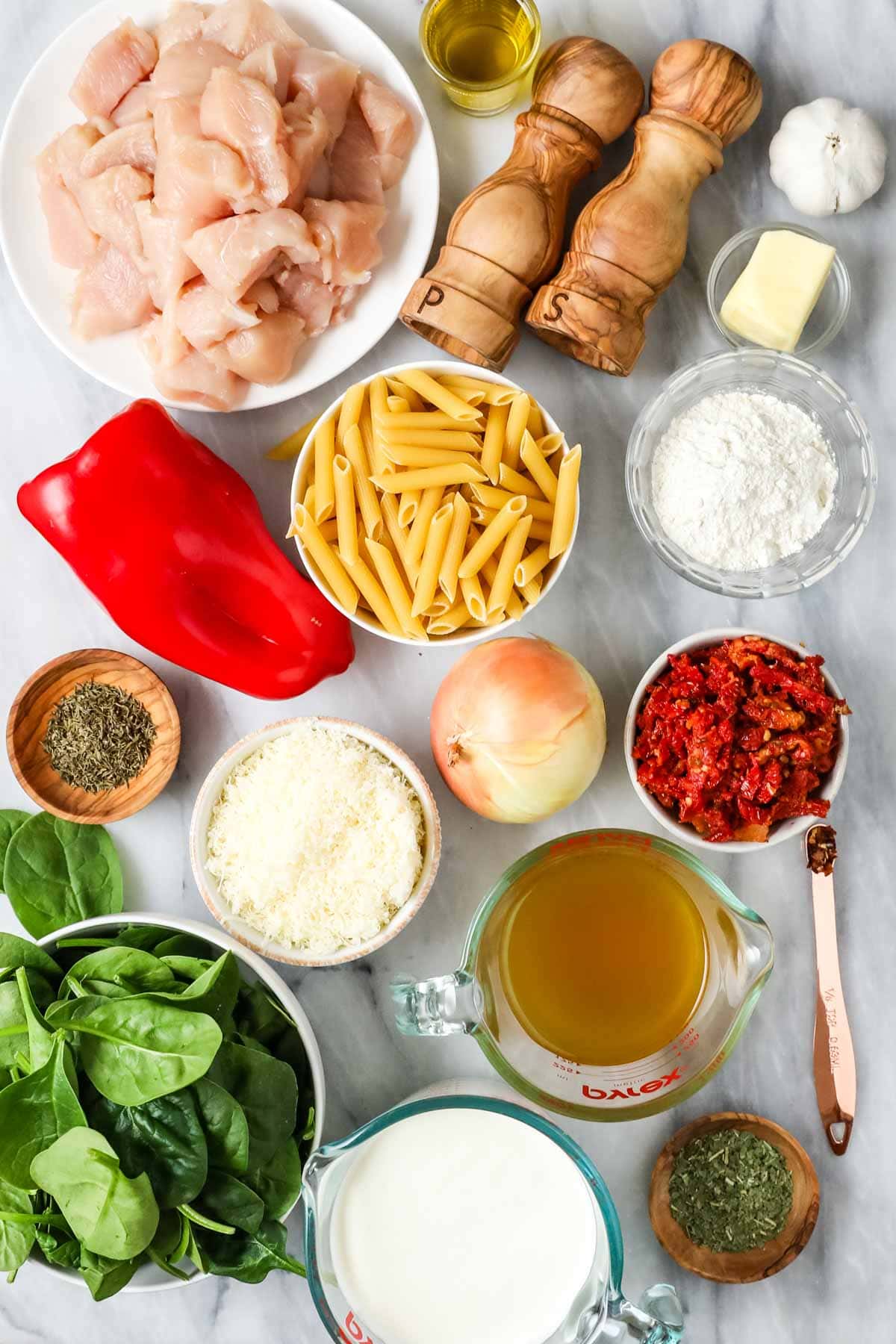 Overhead view of ingredients including chicken, pasta, sun dried tomato, spinach, and more.