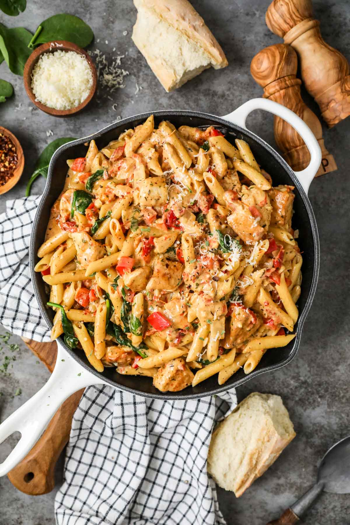 Overhead view of a skillet of pasta made with chicken, sun dried tomatoes, spinach, and more.