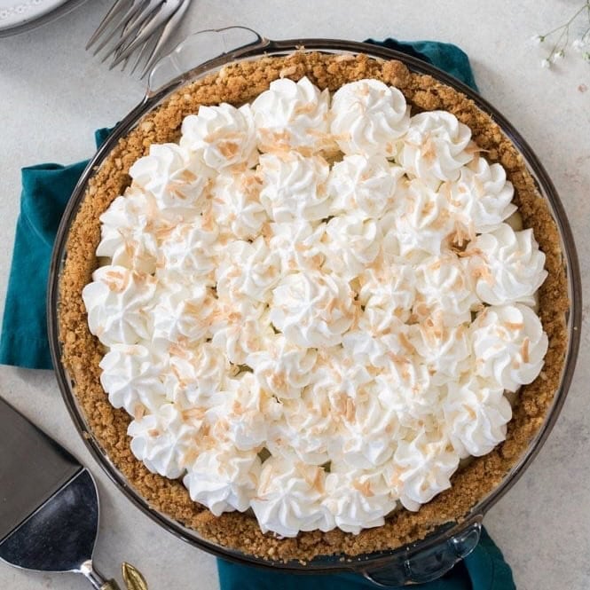 Overhead view of a coconut cream pie topped with whipped cream and toasted coconut.