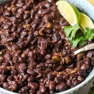 Bowl of cuban-style black beans topped with lime and cilantro.