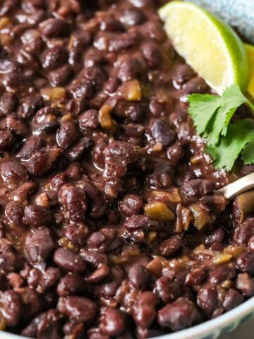 Bowl of cuban-style black beans topped with lime and cilantro.