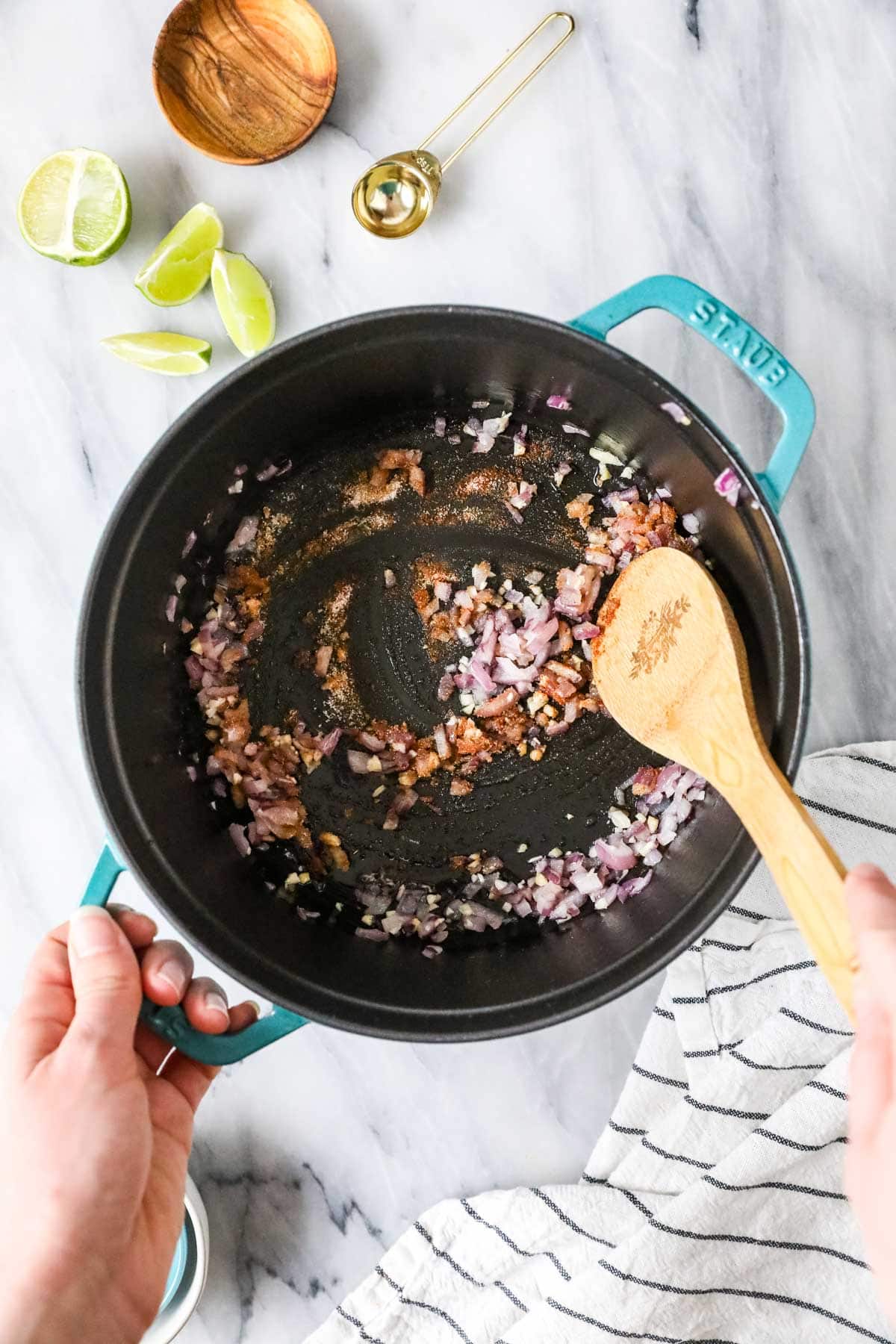 Overhead view of diced red onions sautéing in a pan.