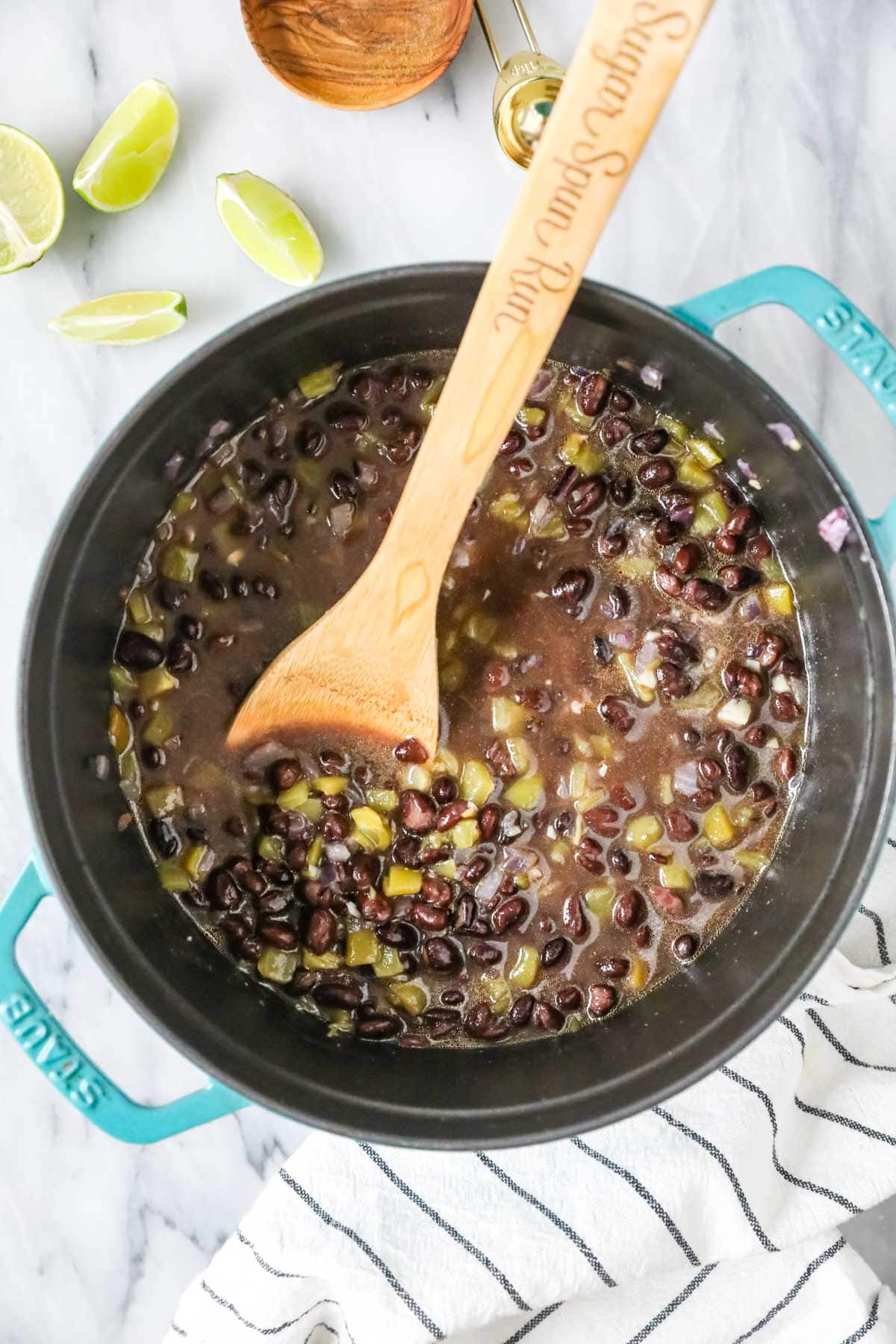 Spoon stirring a pot of black beans.