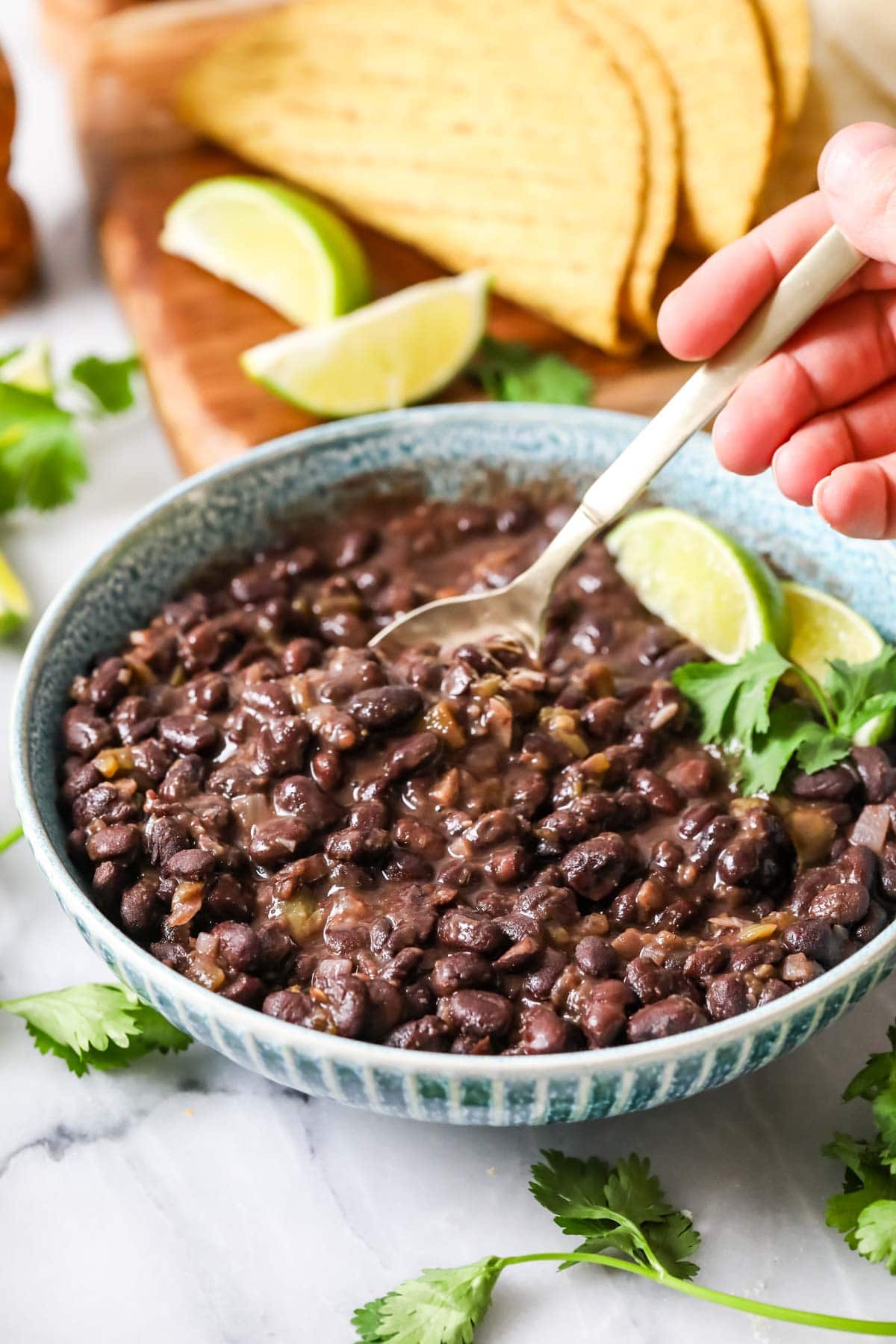 Spoon scooping cuban-style black beans from a bowl.