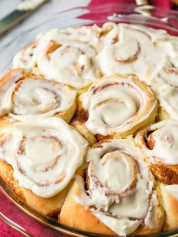 Round pan of homemade cinnamon rolls topped with icing.