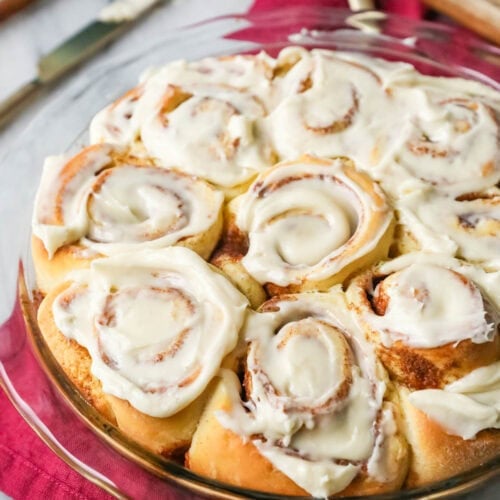 Round pan of homemade cinnamon rolls topped with icing.