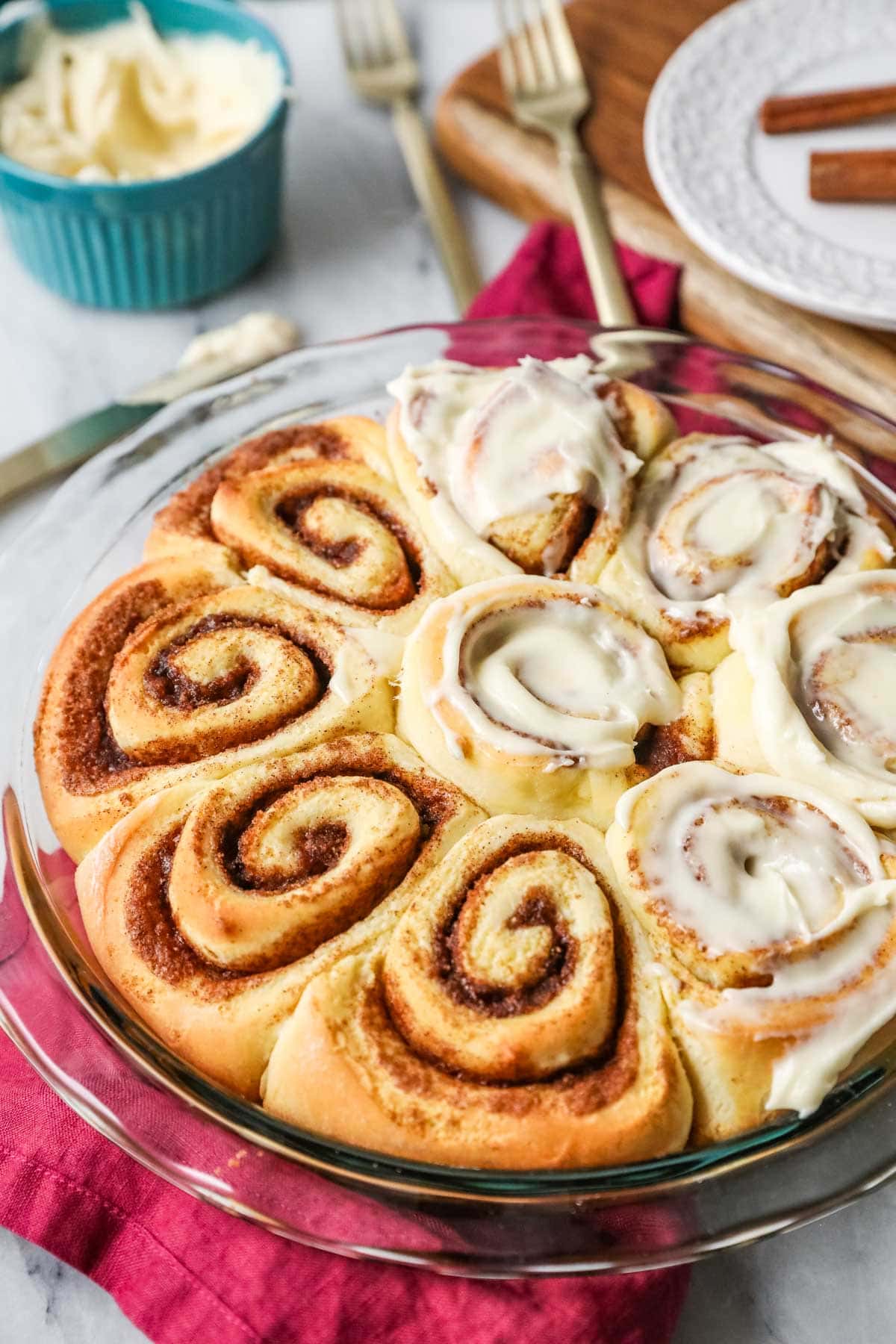 Round pan of homemade cinnamon rolls, half of which are unfrosted.