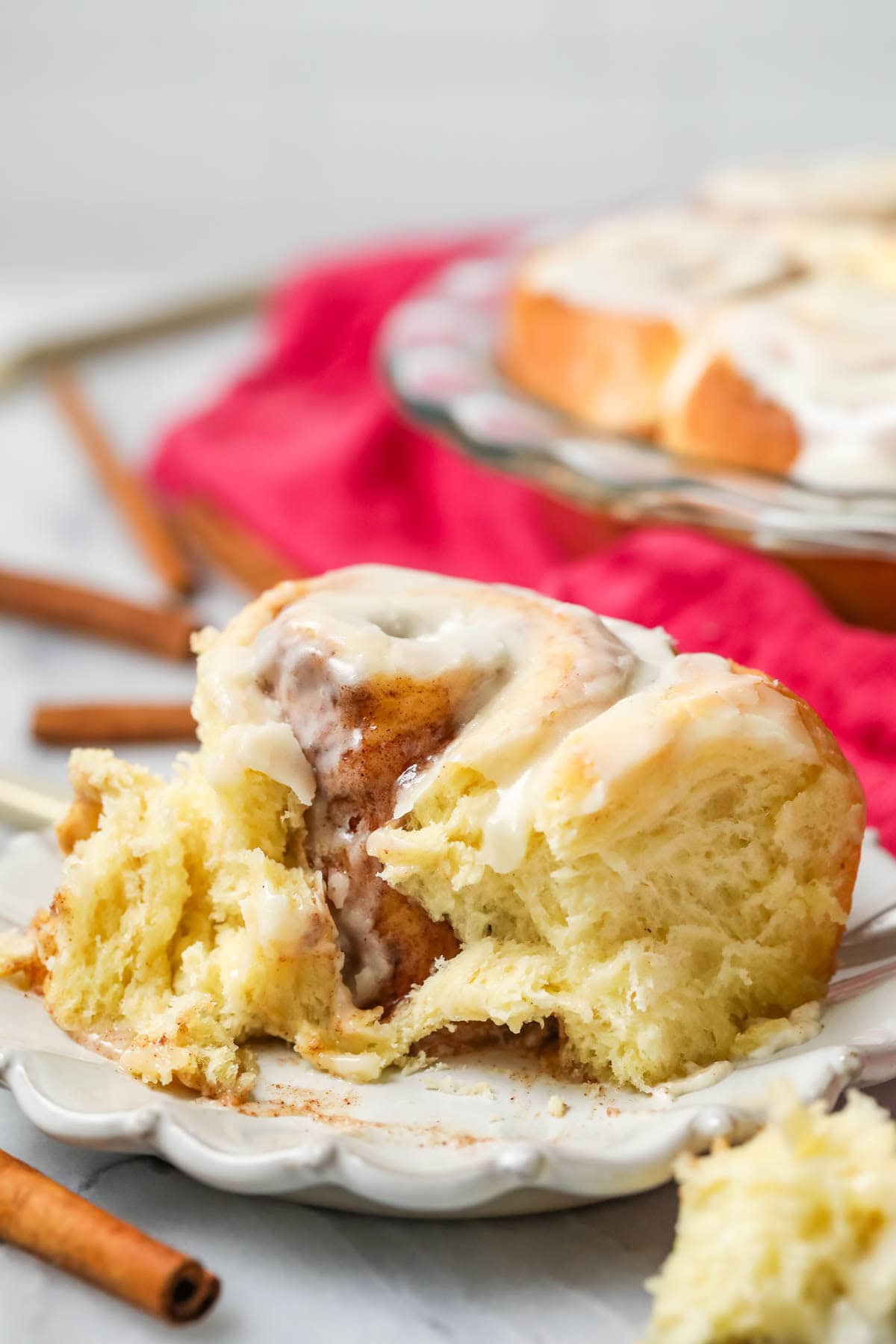 Homemade cinnamon roll missing a bite on a plate.