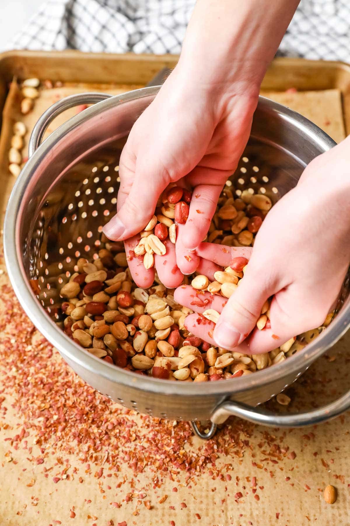 Hand move peanuts in a colander to remove the skin.