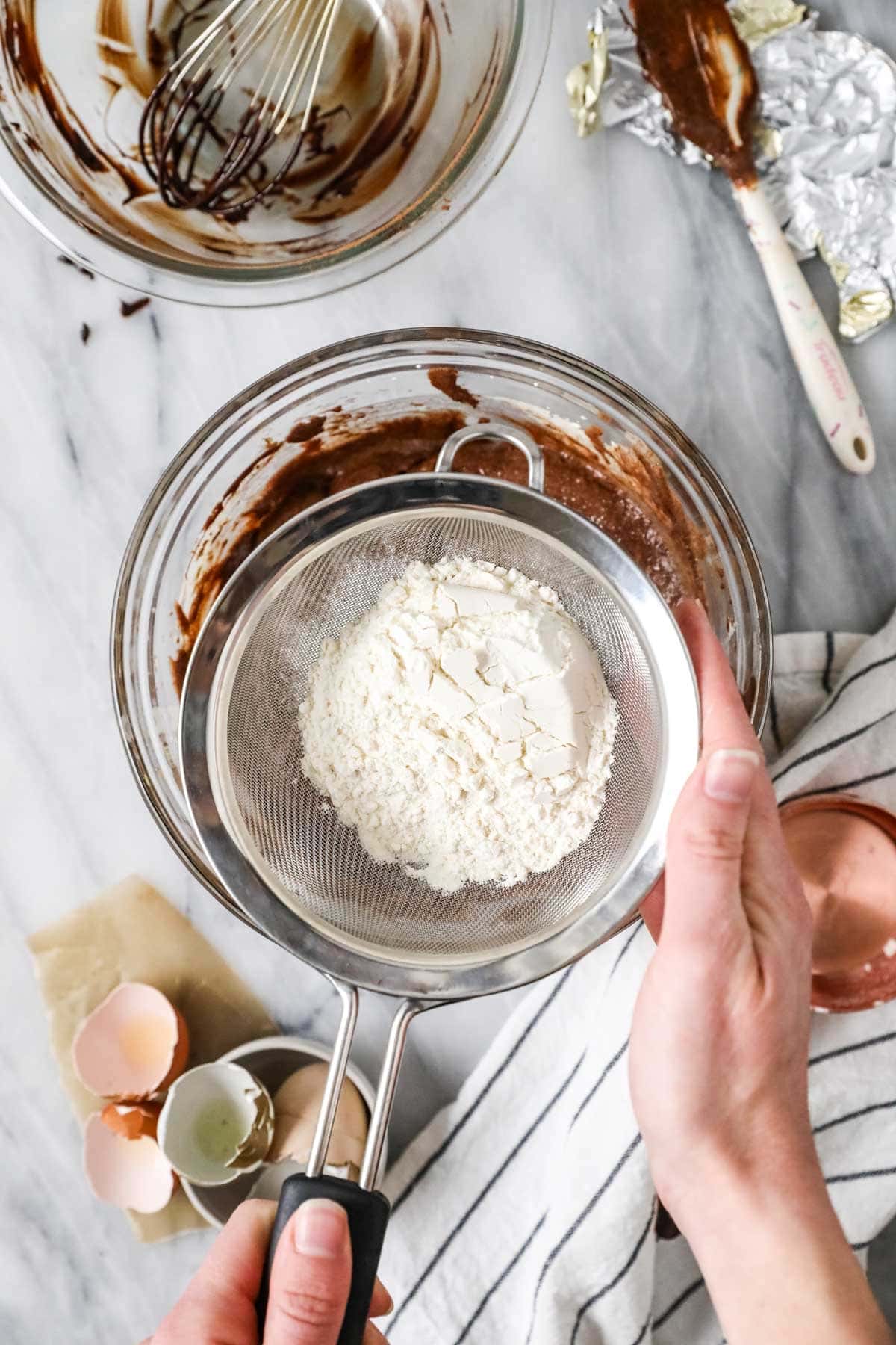 Overhead view of flour being sifted into peanut butter brownie batter.