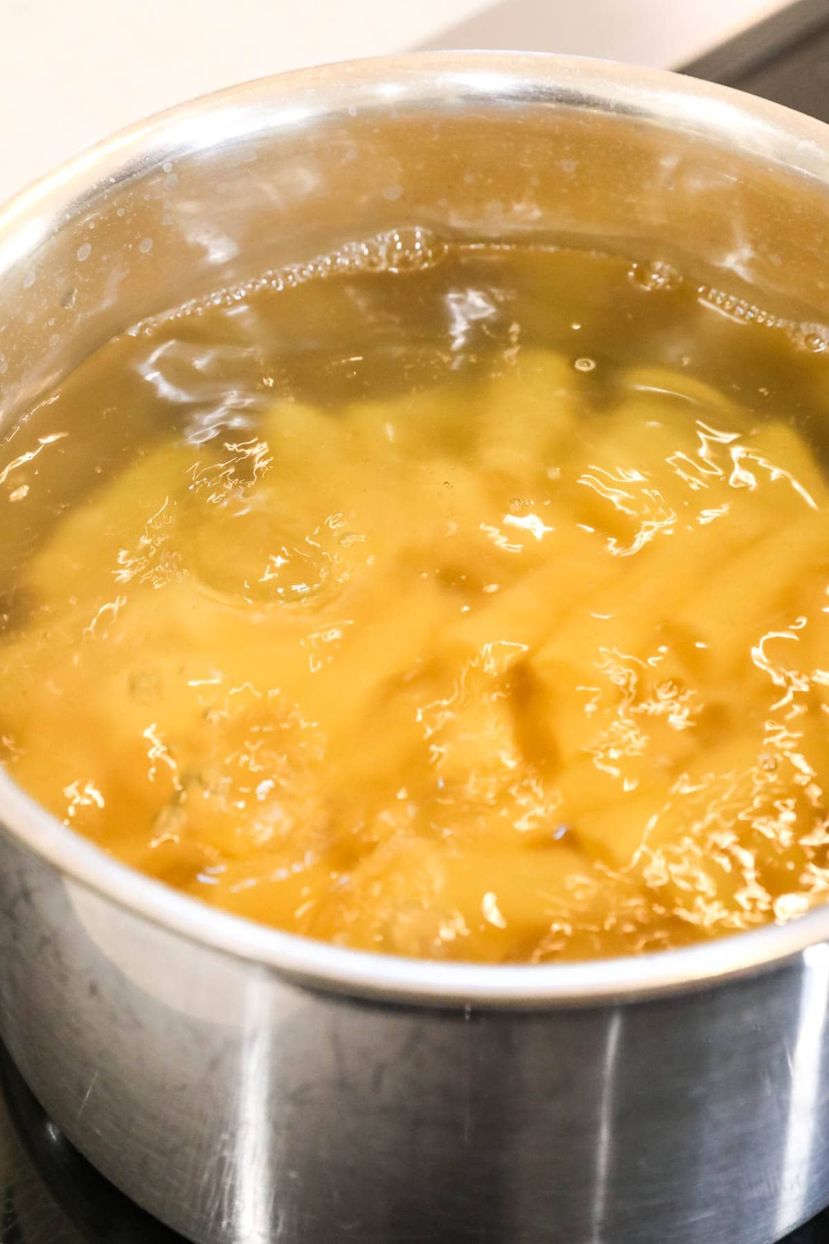 Close-up view of rigatoni noodles boiling in water.