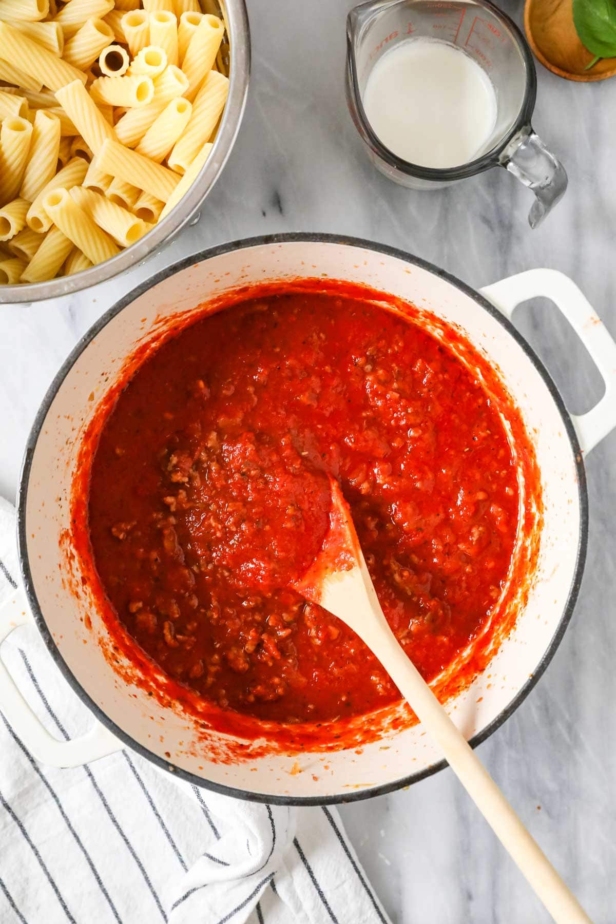 Overhead view of a pot of tomato sauce made with sausage and onions.