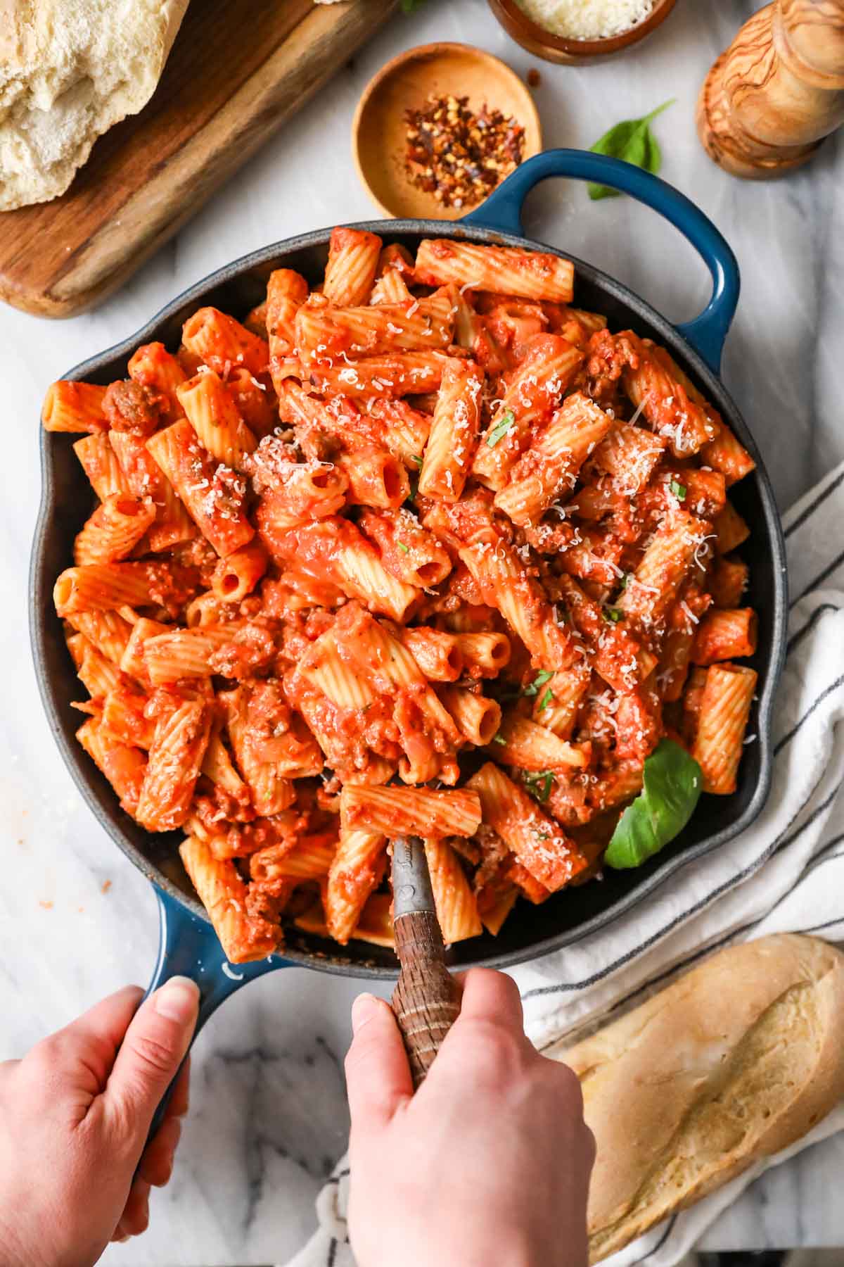 Overhead view of a skillet of homemade rigatoni topped with freshly grated parmesan cheese.