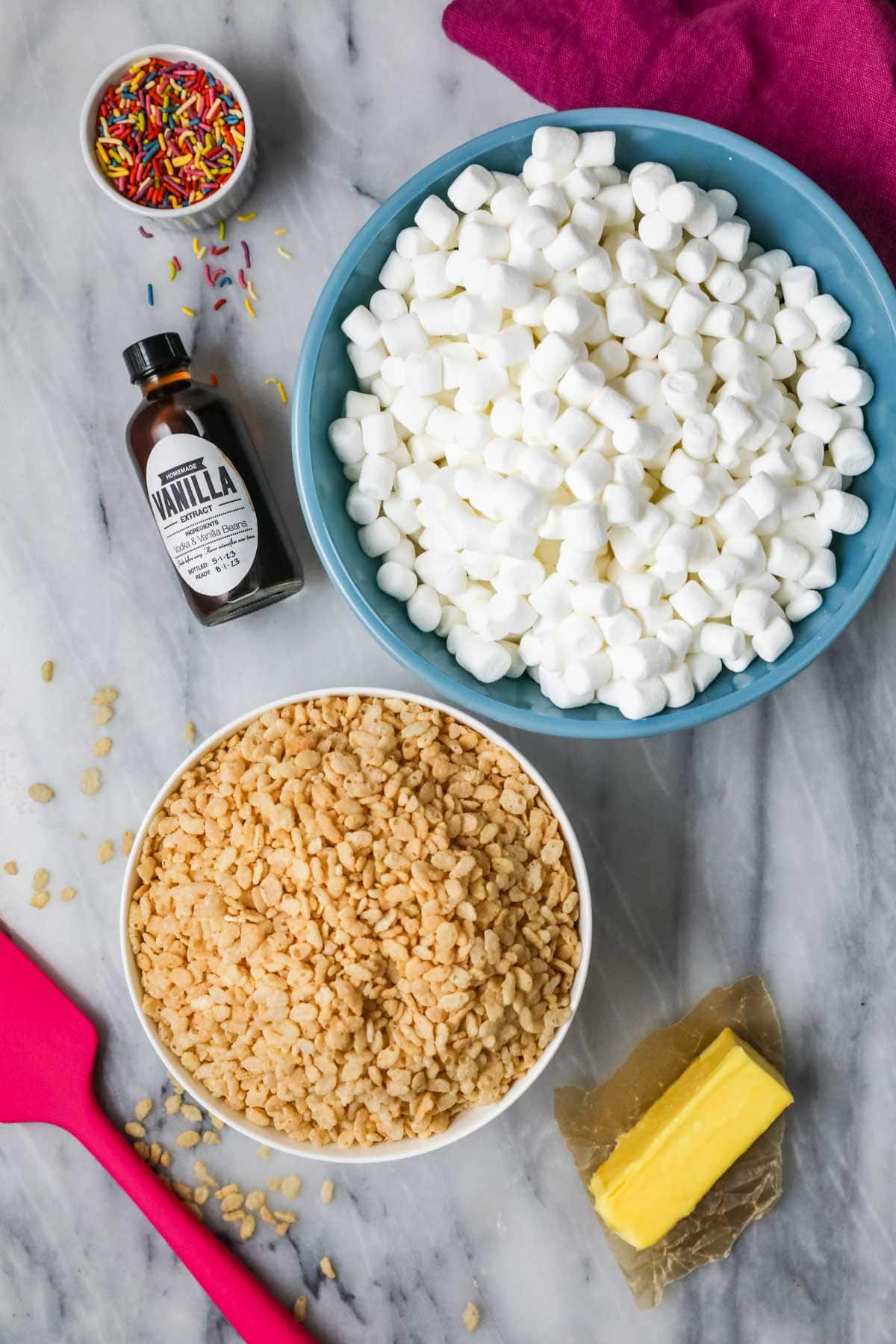 Overhead view of ingredients including rice krispie treats cereal, marshmallows, butter, and vanilla.