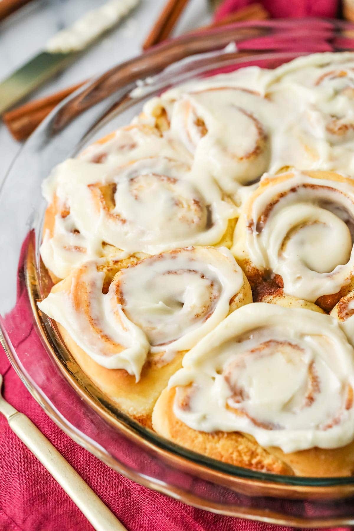 Close-up view of a round pan of homemade cinnamon rolls topped with icing.