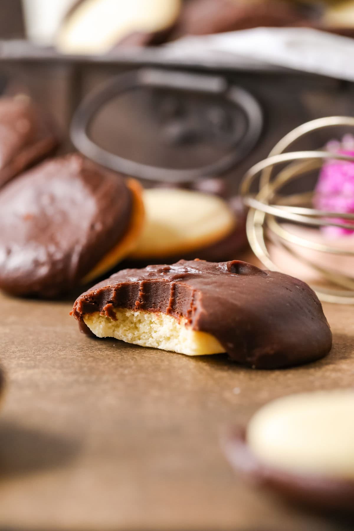 Bite missing from a homemade berger cookie topped with a generous amount of chocolate fudge frosting.