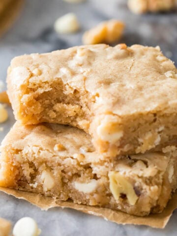 Two blondies from my blondie recipe, stacked on top each other, one with a bite missing to show the chewy center