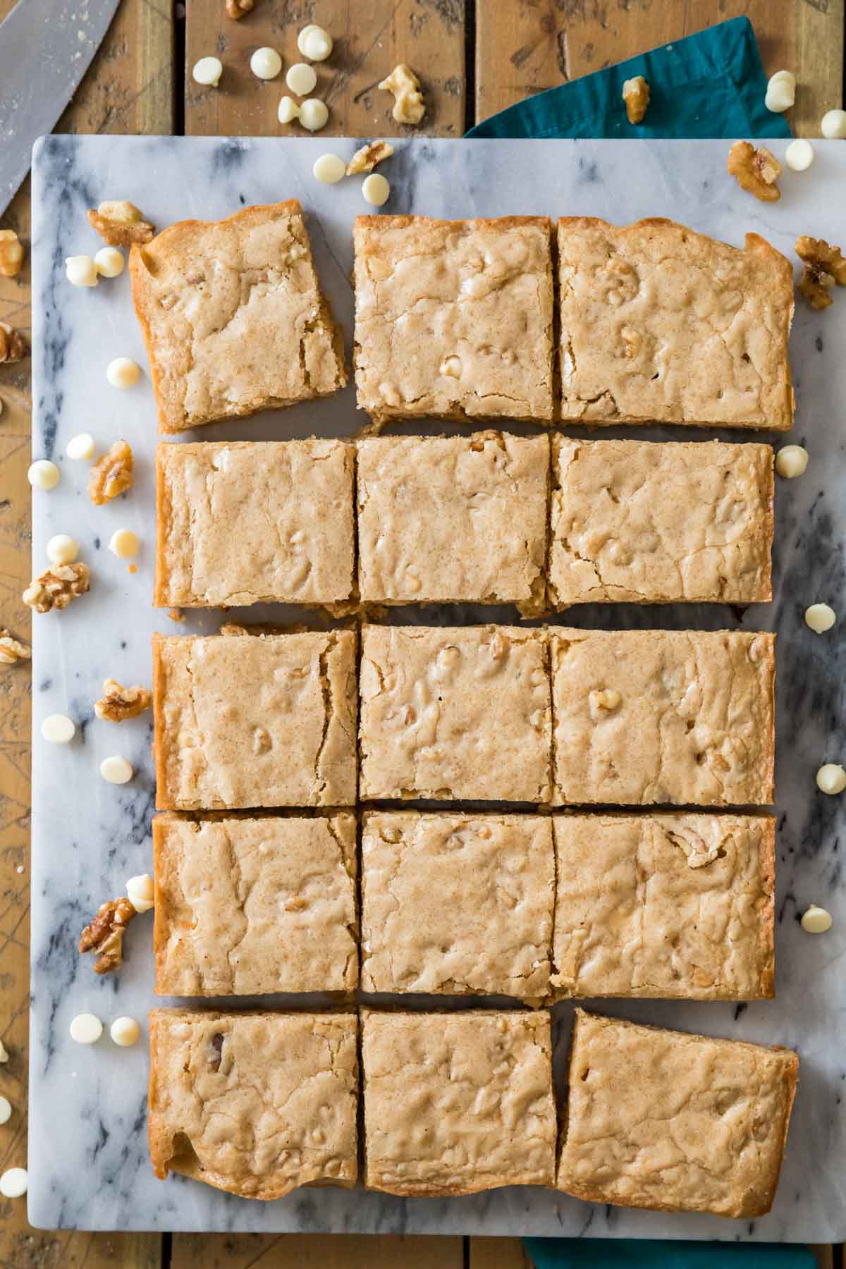 Overhead view of blondies on a white marble cutting board, cut into 15 pieces