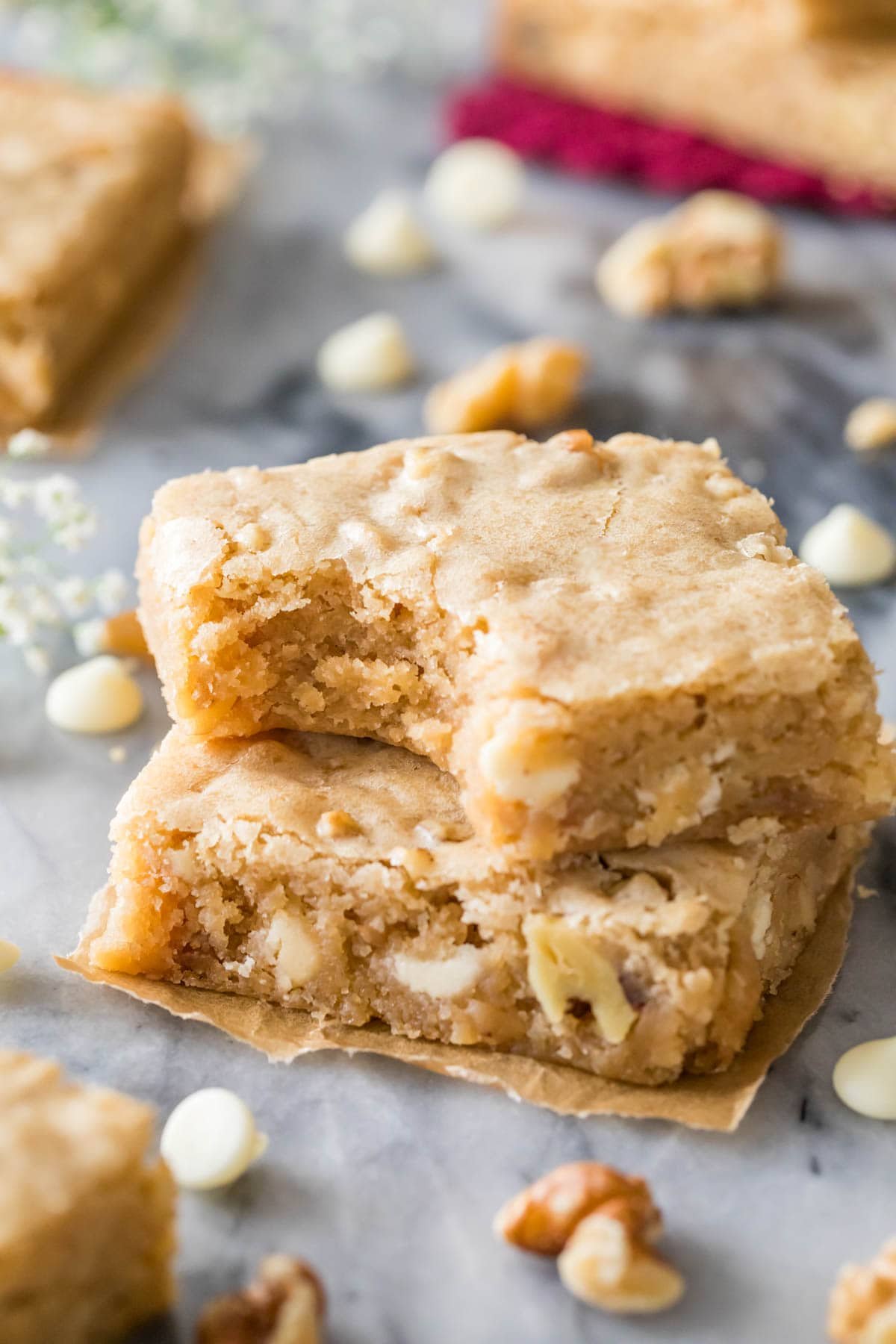 Two blondies from my blondie recipe stacked on top each other, one missing a bite, showing the soft and gooey center.