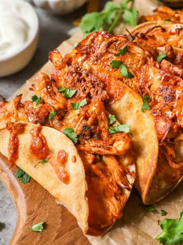Crispy chicken tacos on a wood cutting board.