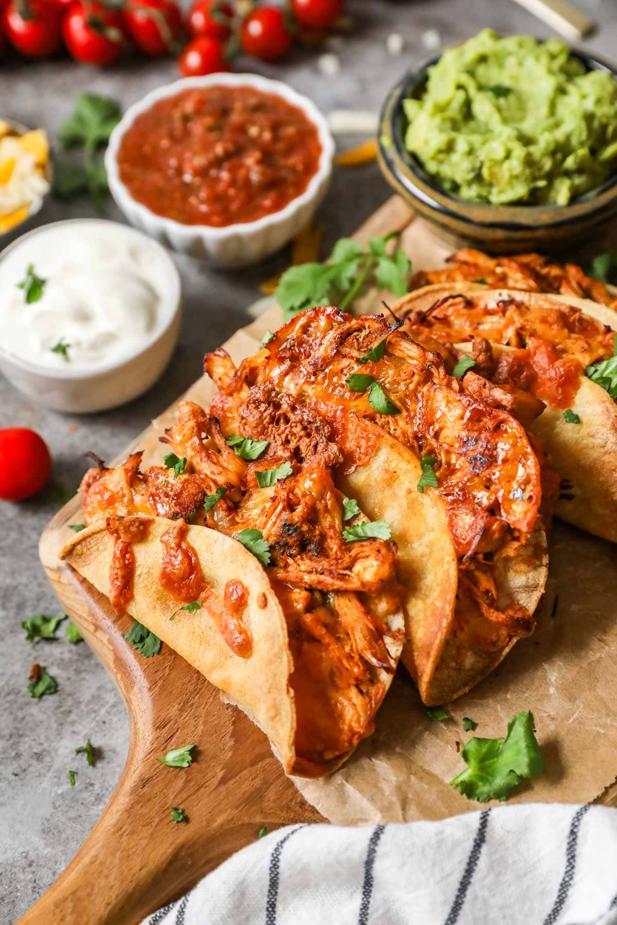 Crispy chicken tacos on wooden cutting board.